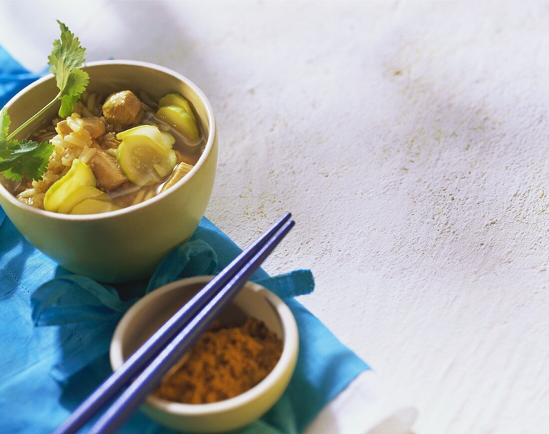 Zucchini-Geflügelsuppe mit Reis im Schälchen; Currypulver