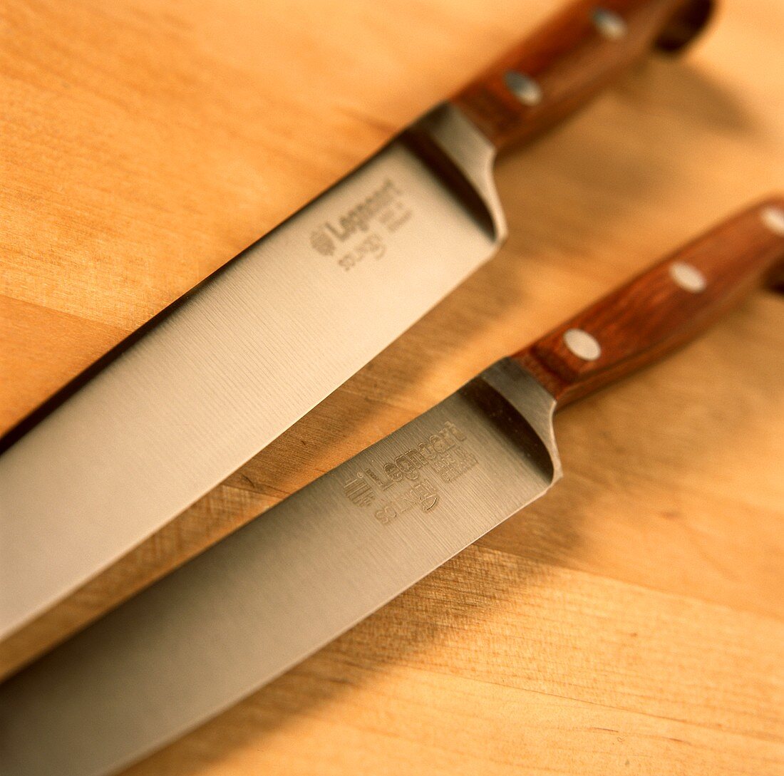 Zwei Messer mit Holzgriffen auf Holzuntergrund