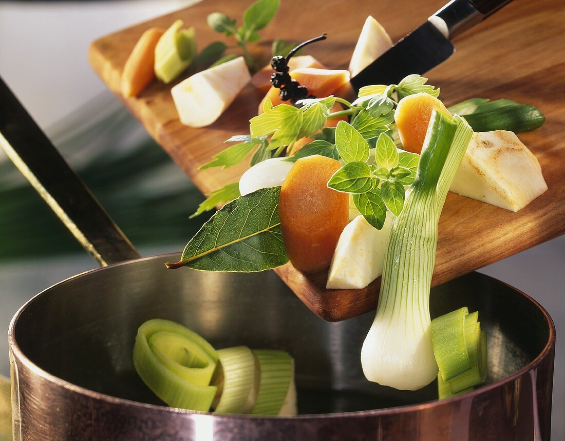 Soup vegetables falling from the chopping board into a pan