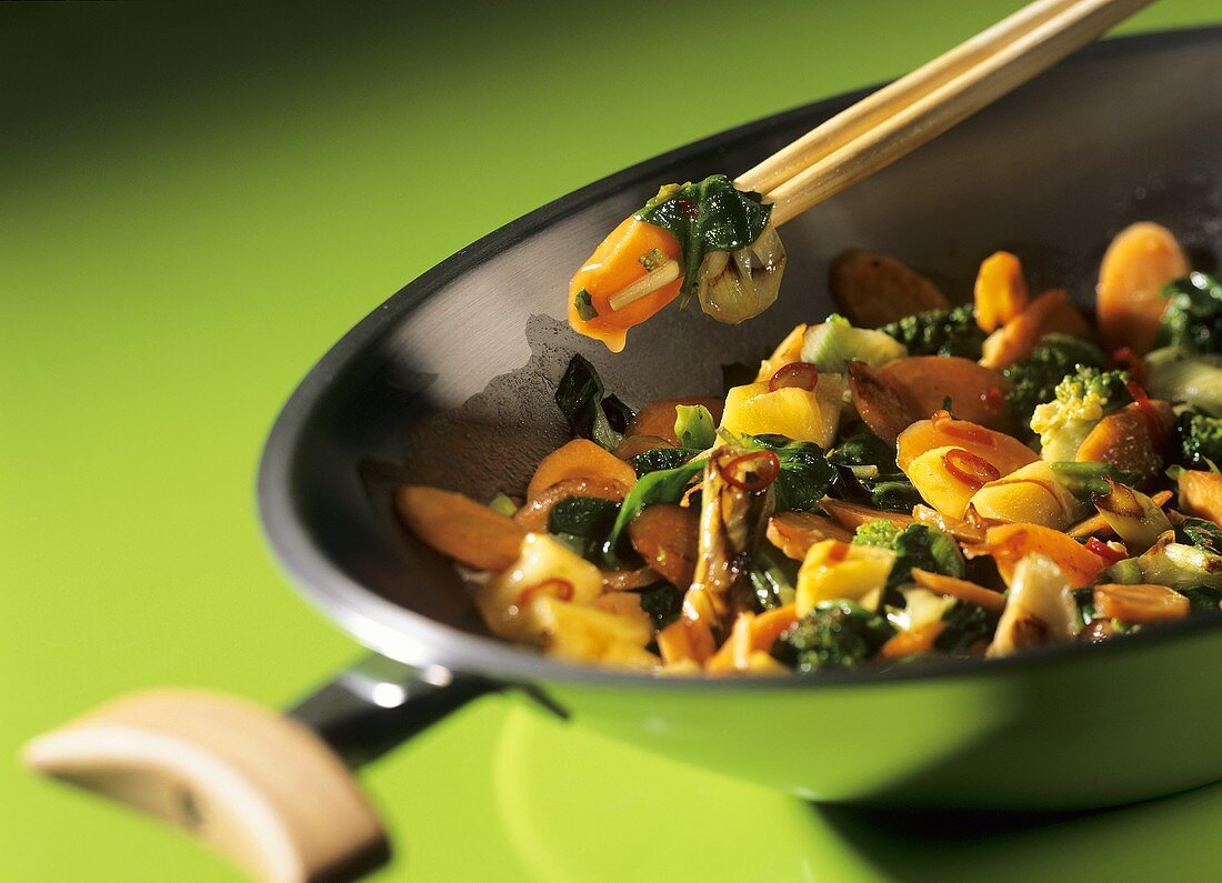 Sweet and sour Thai vegetables in a wok and on chopsticks