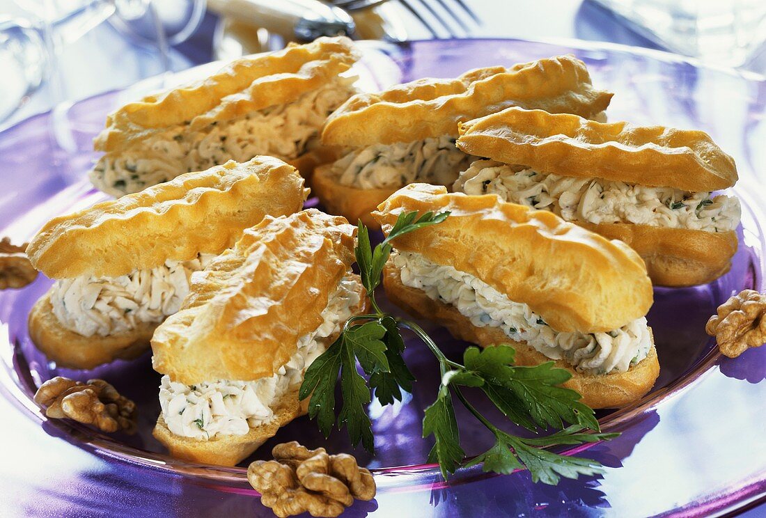 Eclairs with cheesy cream filling & walnut kernels on plate