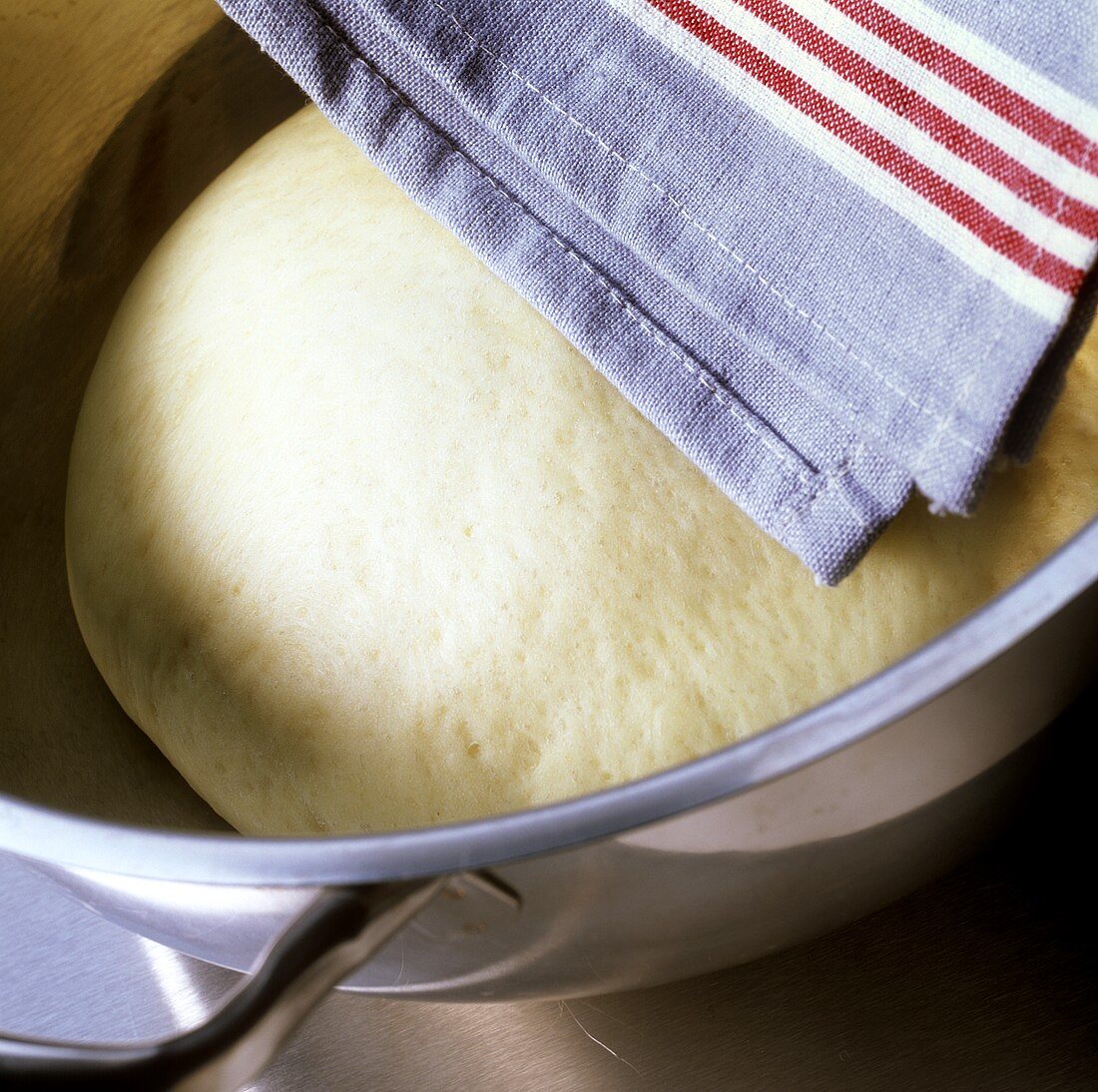 Leavened dough in a bowl with a cloth over it