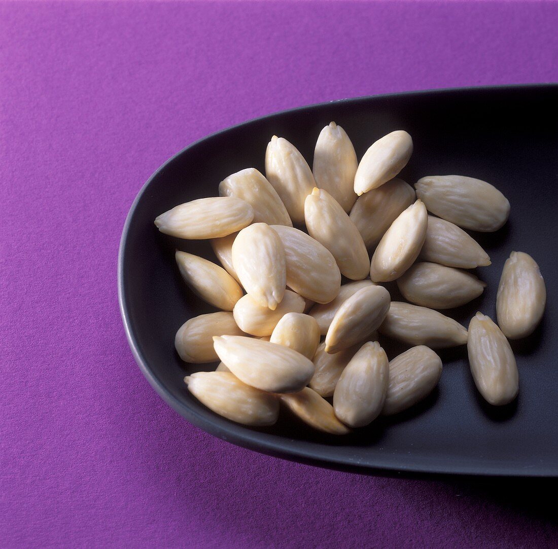 Blanched almonds in a small black bowl