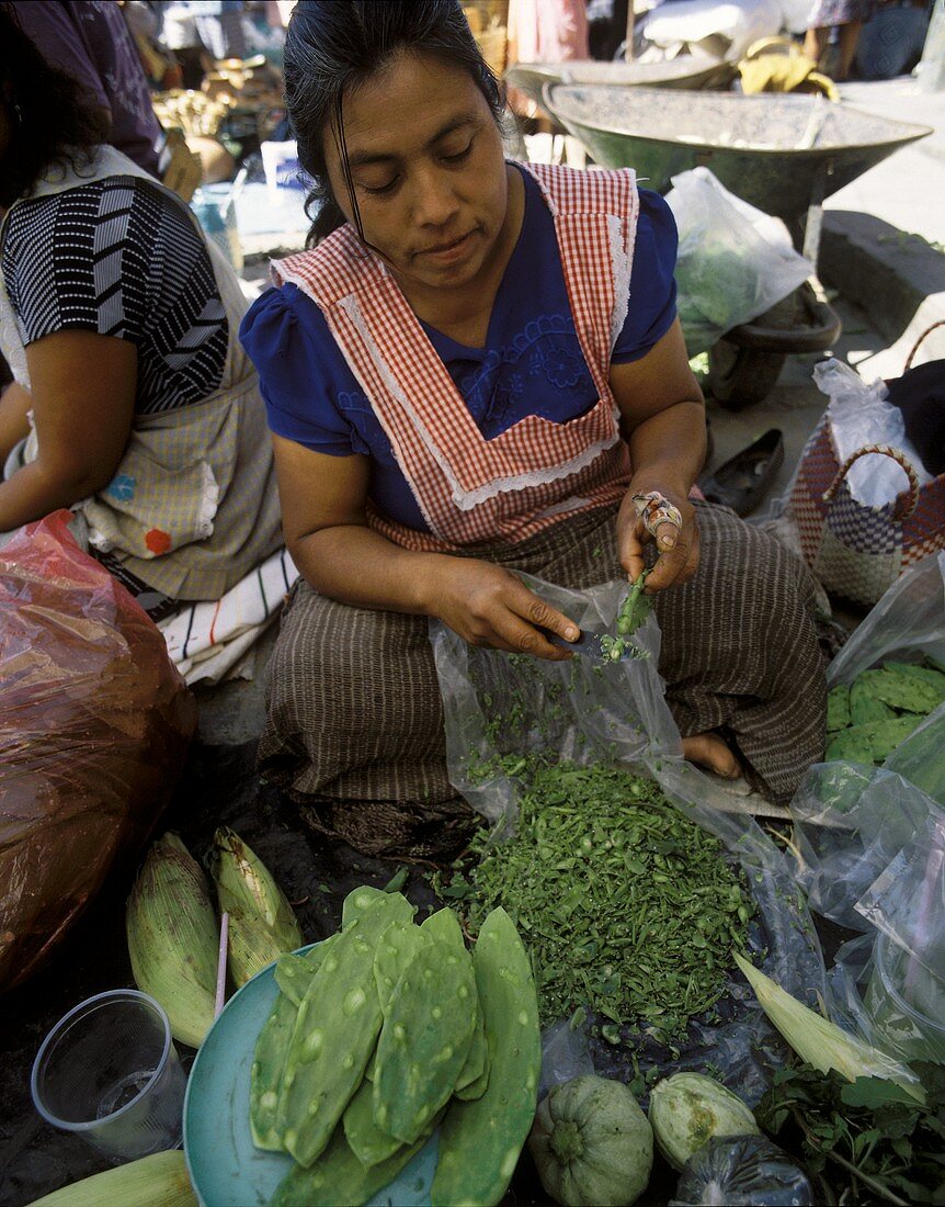 Frau pult Kaktusfeigenblätter auf einem Markt in Mexiko
