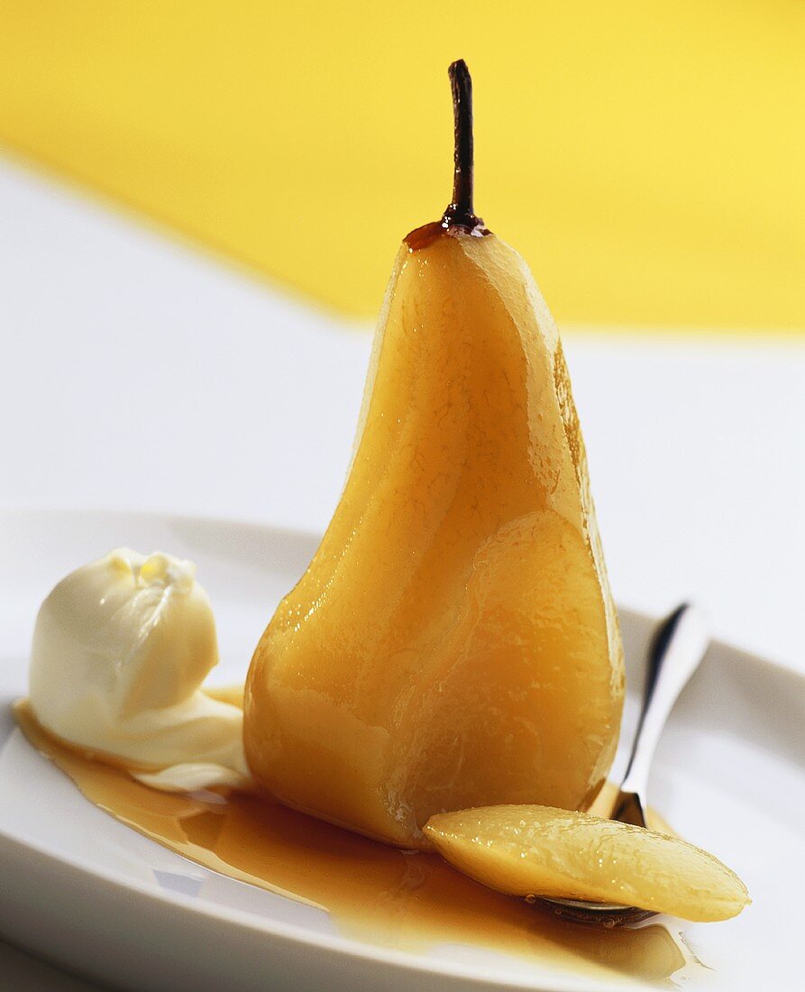 Poached pear with cream on plate with spoon