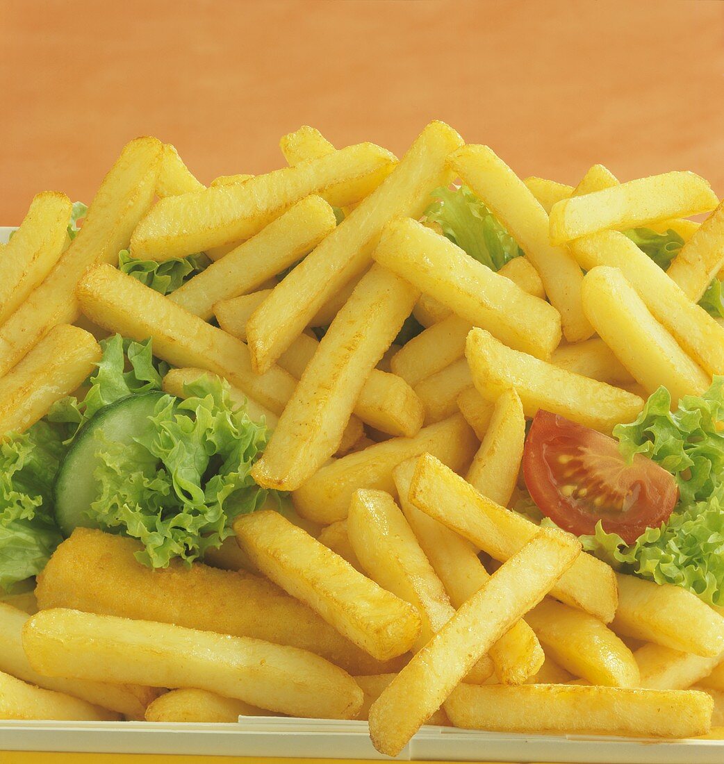 Pommes frites mit Salatblättern, Gurke und Tomate