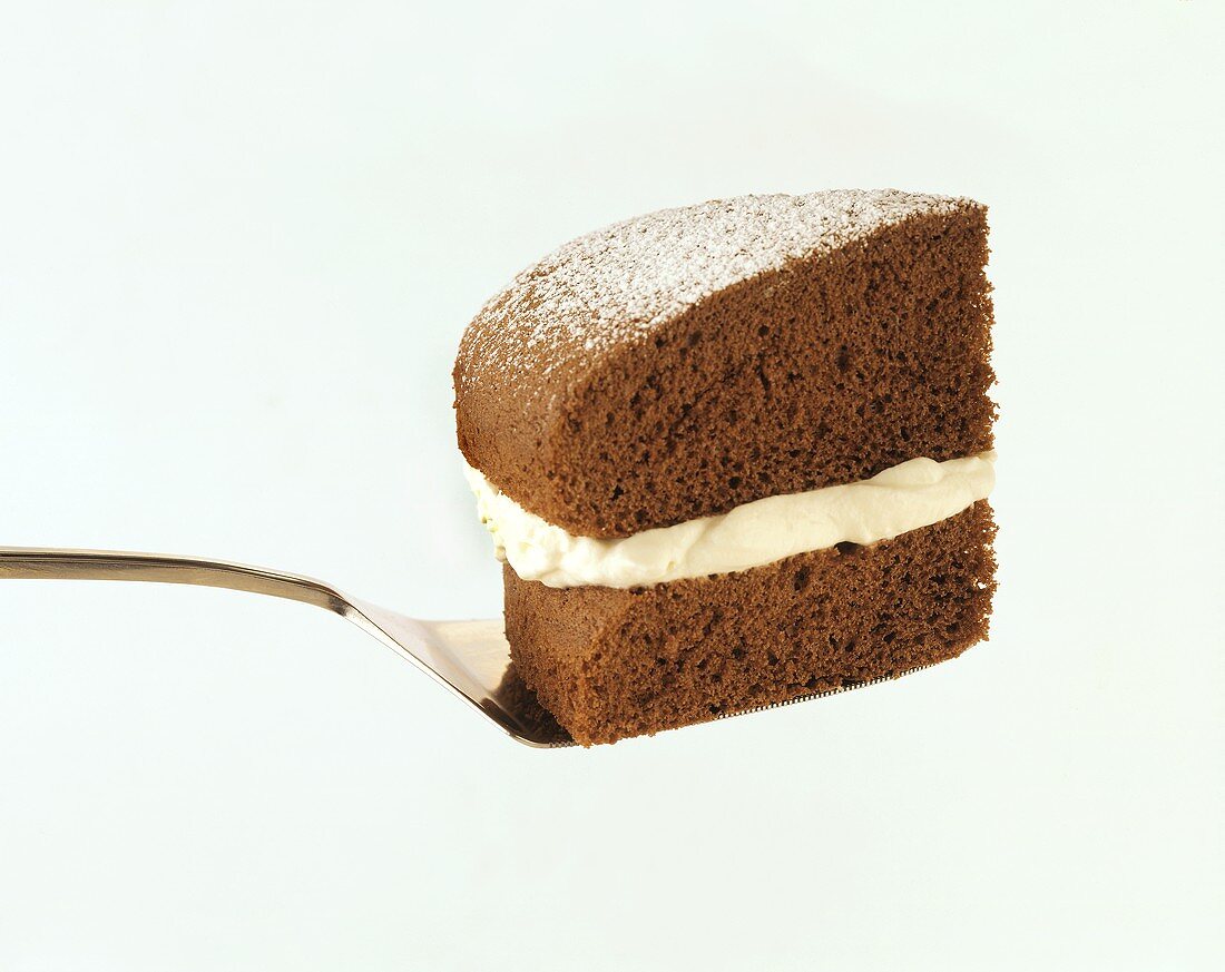 Ein Stück Schokoladenkuchen mit Sahneschicht auf Kuchenheber