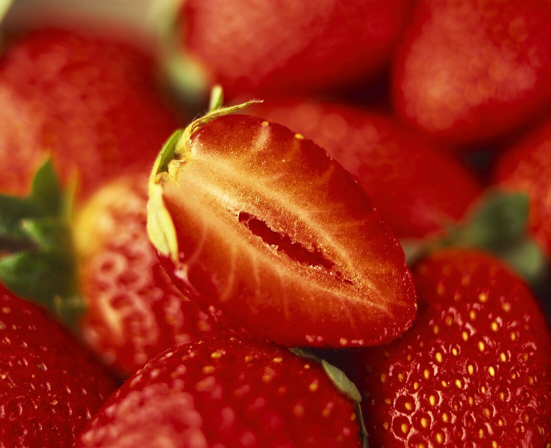 Eine Erdbeerenhälfte auf ganzen Erdbeeren