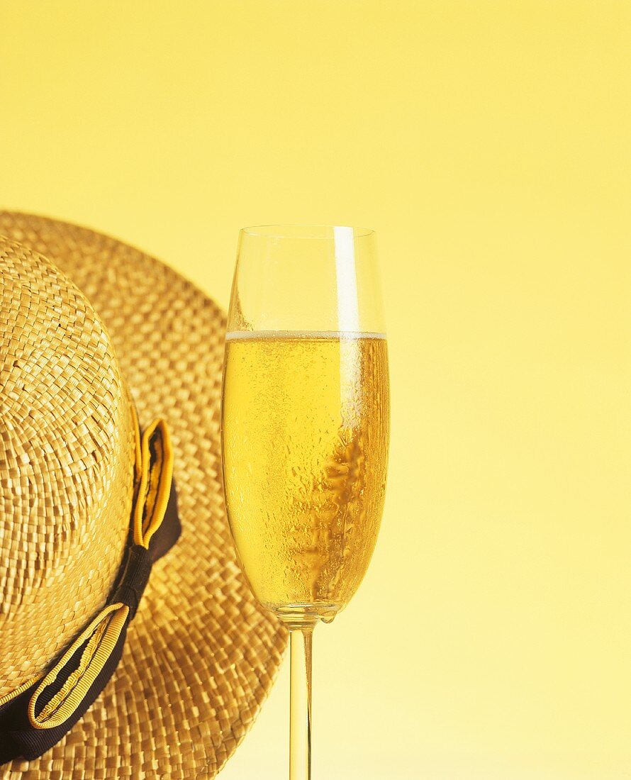 A champagne glass beside a straw hat