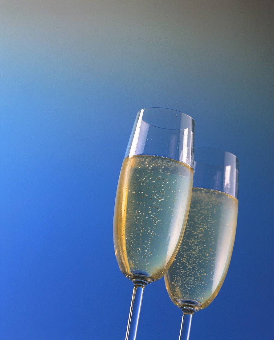 Two champagne glasses against a blue backdrop