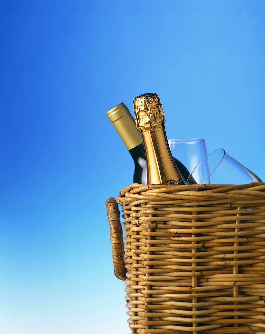 Champagne bottle and wine bottle with glasses in picnic basket