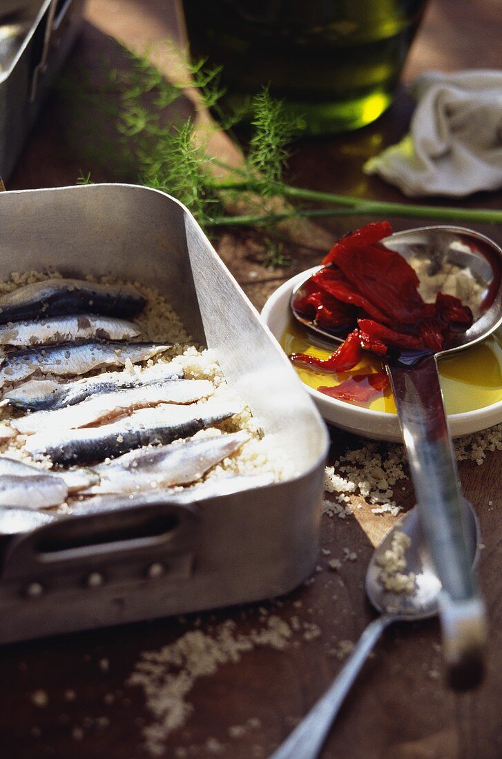 Marinierte Sardinen im Bräter; getrocknete Tomaten; Öl