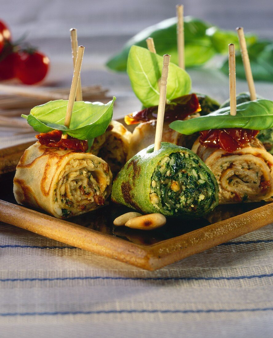 Mozzarella- and green crespelle on cocktail sticks with basil