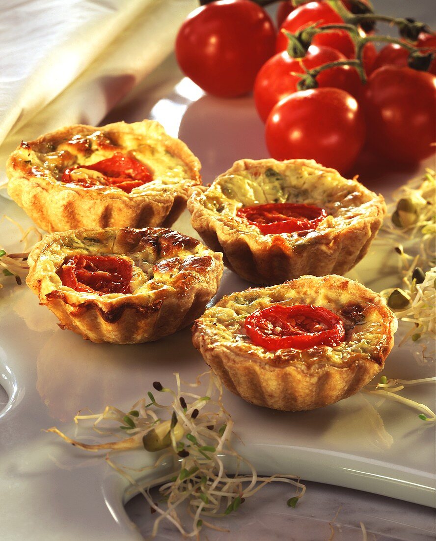 Sprout & quark quiches, topped with tomatoes, on marble board