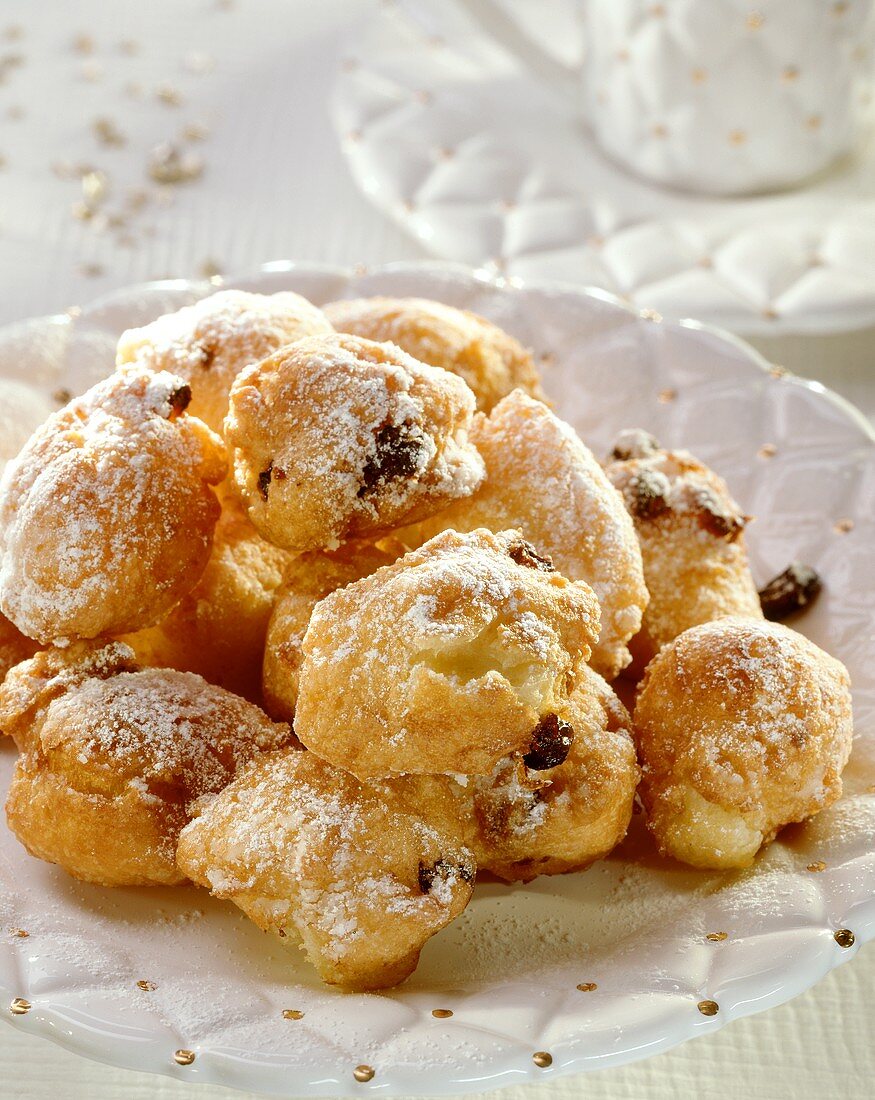 Grappa fritters with raisins & icing sugar on white plate