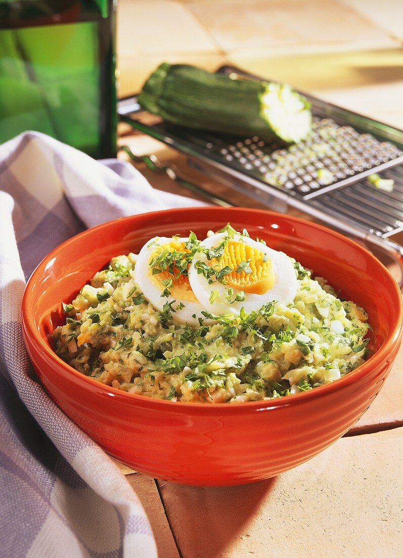 Courgette spread with boiled egg in red bowl