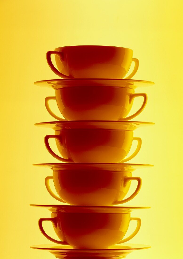 Pile of soup plates against a yellow backdrop