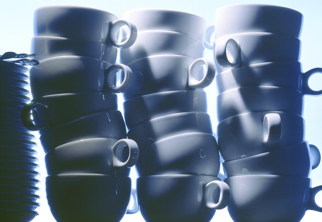Three piles of cups & a pile of plates with cutlery (blue)
