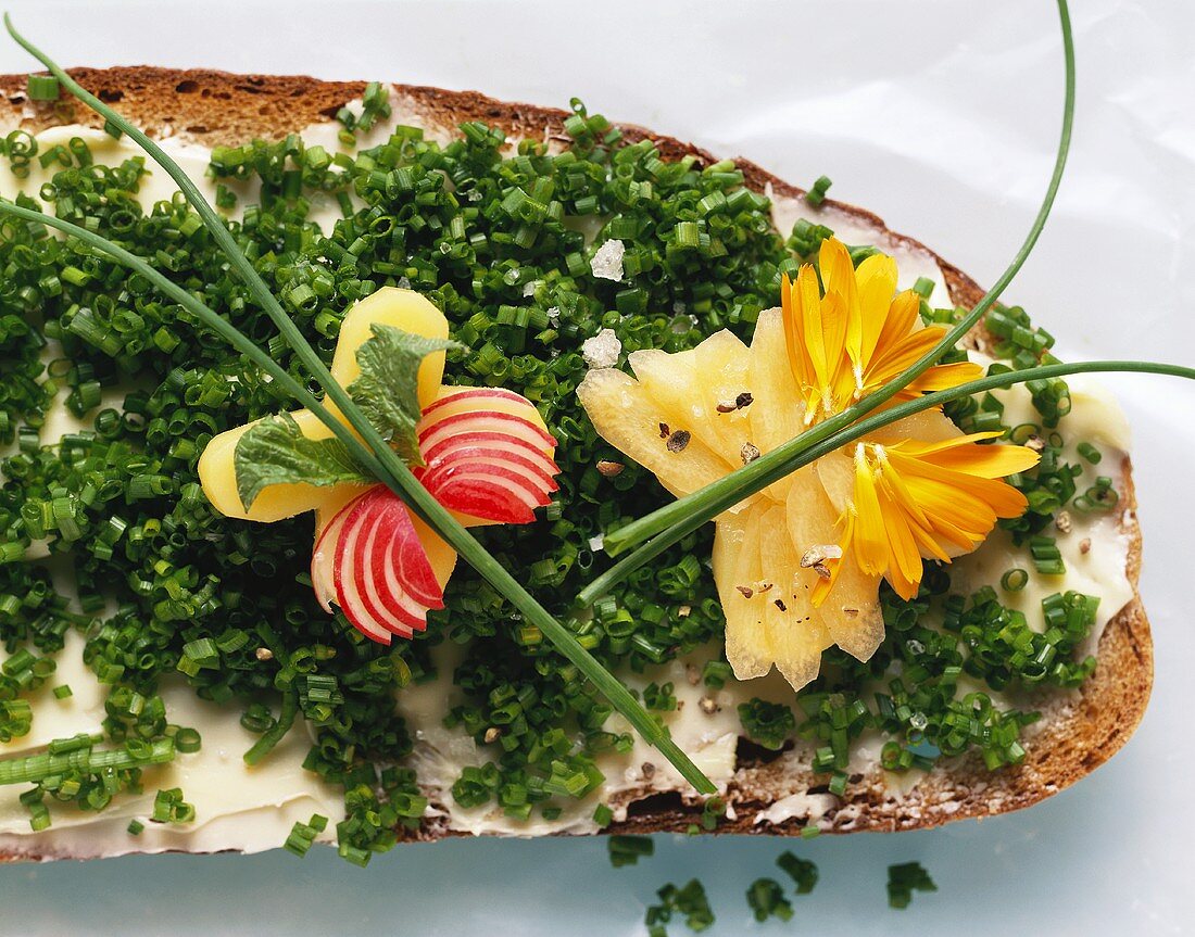 Schnittlauchbrot, dekoriert mit Käseschmetterling und Blüten