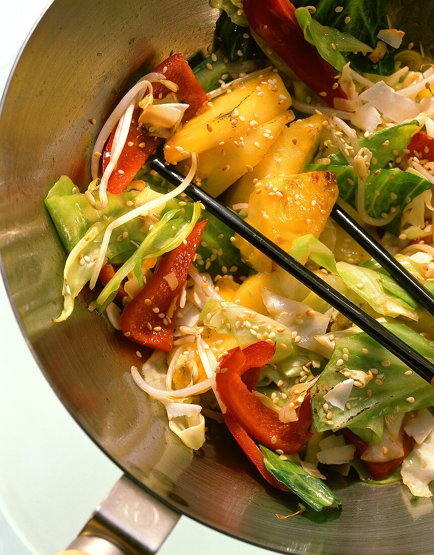 Cabbage stir-fry with pepper, pineapple and sprouts in a wok