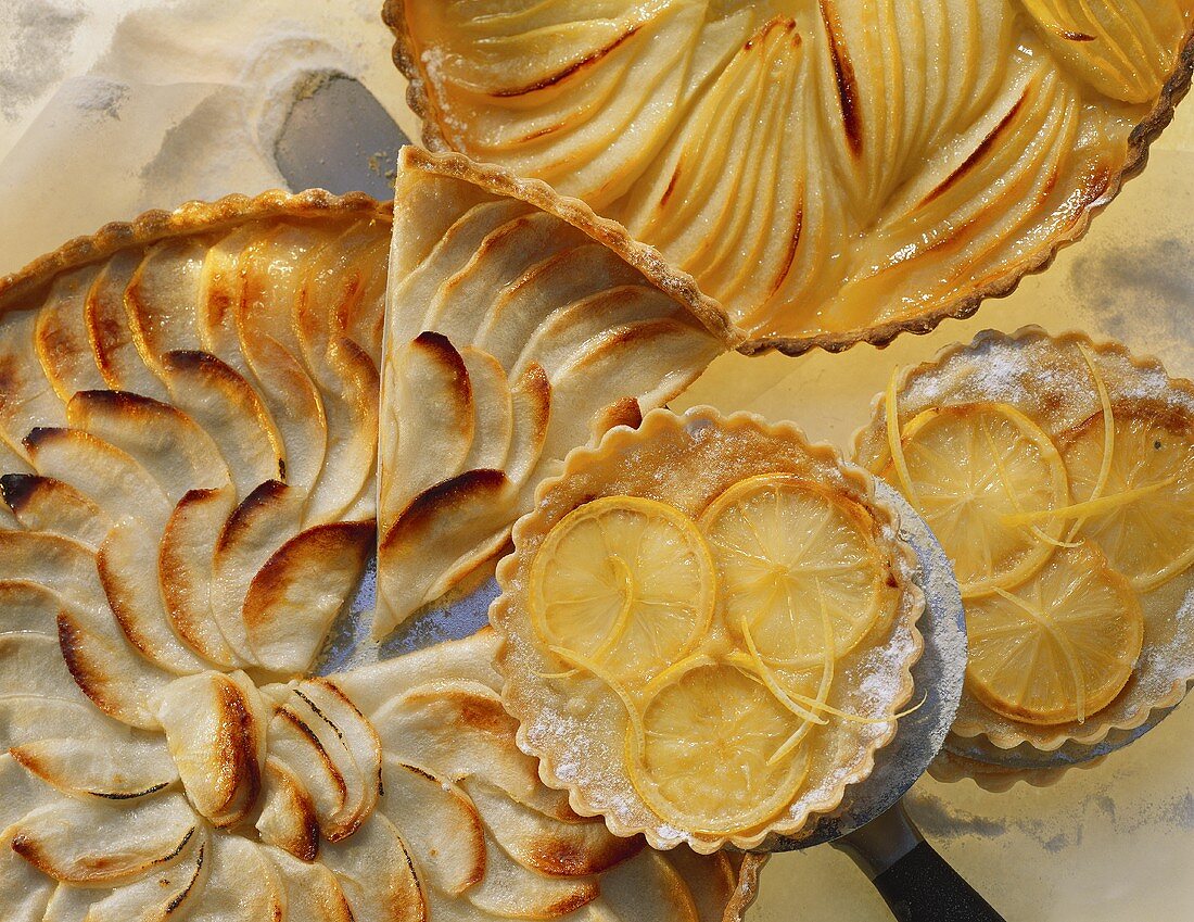 Apple tart (a piece cut), lemon tartlets, pear tart