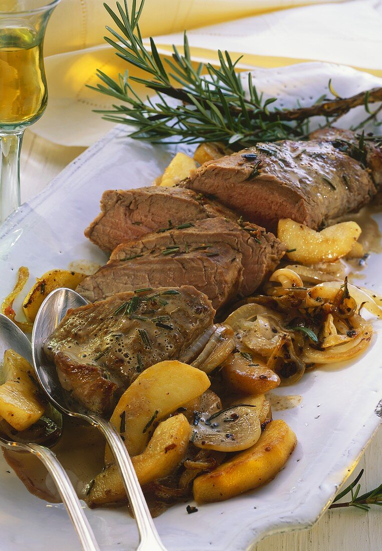 Pork fillet with apples, onions and rosemary on platter