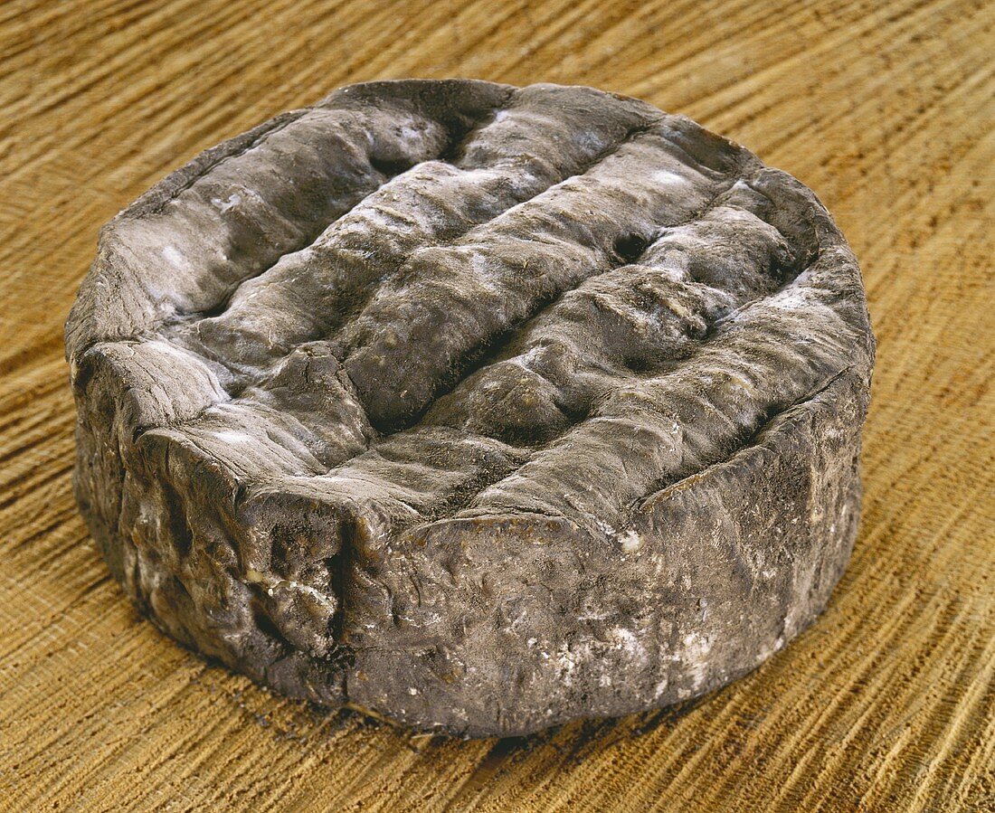 Olivet cendre, a French soft cheese, on a brown background