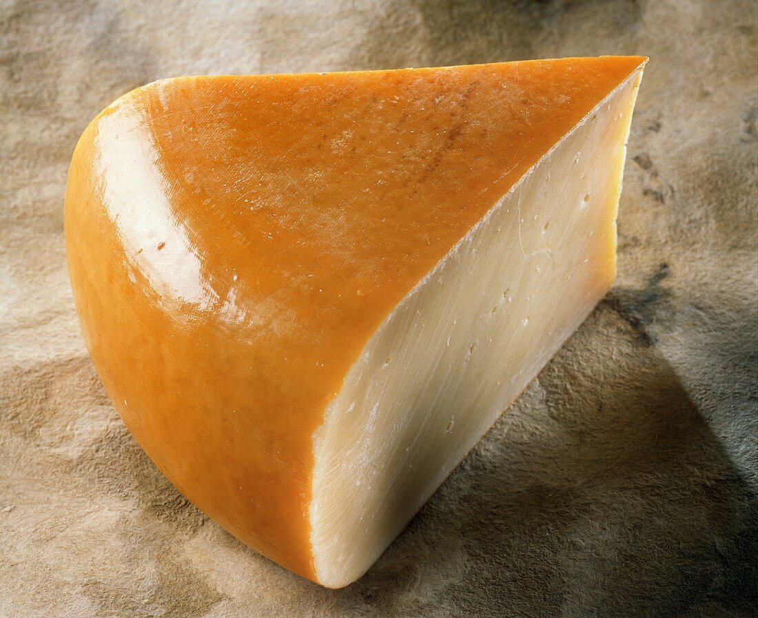 A piece of Gouda on light-brown background