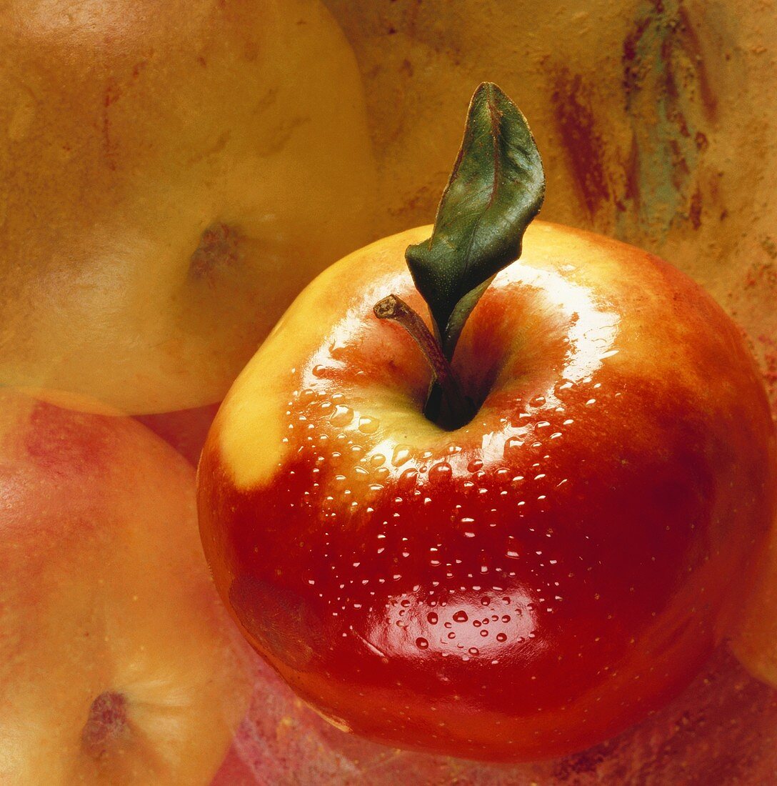 Apfel mit Wassertropfen auf künstlerisch bemaltem Untergrund