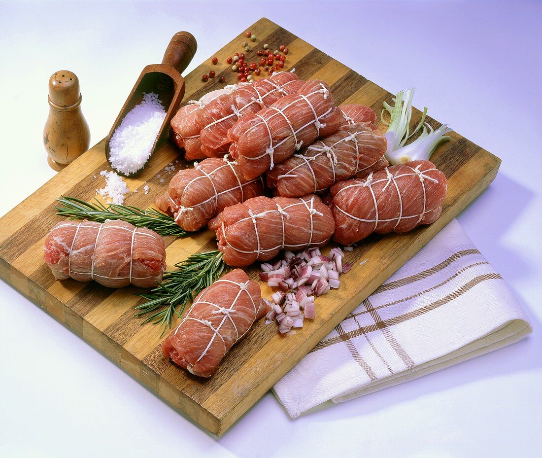 Raw veal roulades with onions and spices on wooden board