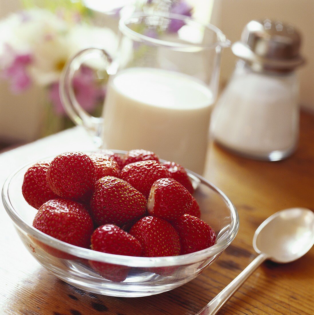 Strawberries in a bowl, jug of cream behind