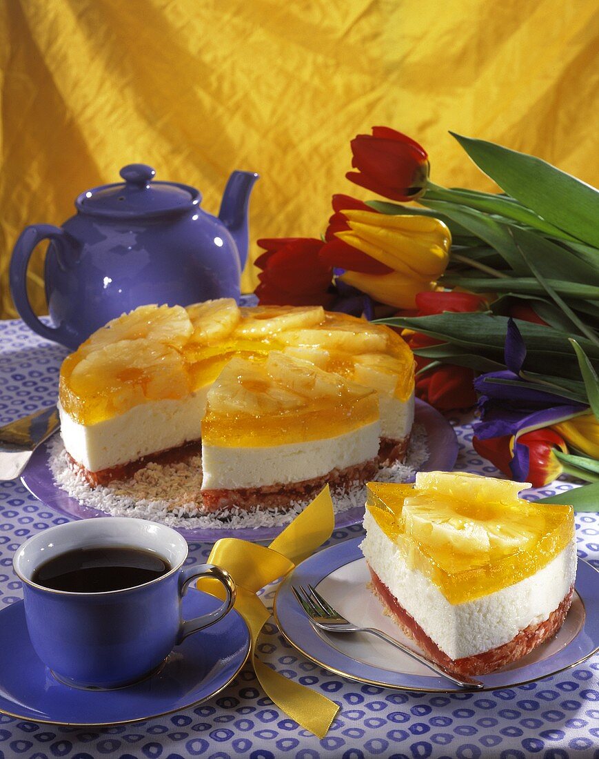 Cheesecake with pineapple and a cup of coffee; tulips