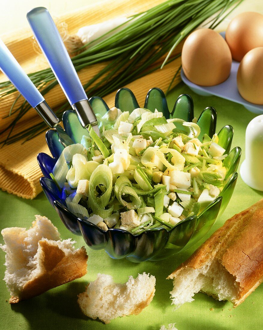 Leek salad with chopped eggs in dish; baguette