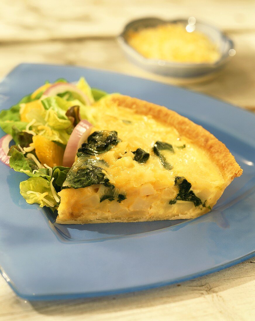 A piece of potato and spinach quiche with lettuce on plate