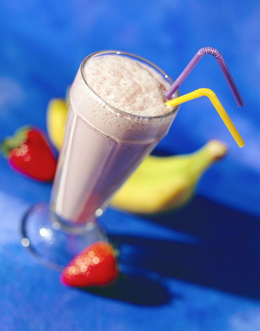 Strawberry and banana shake in a glass with straws