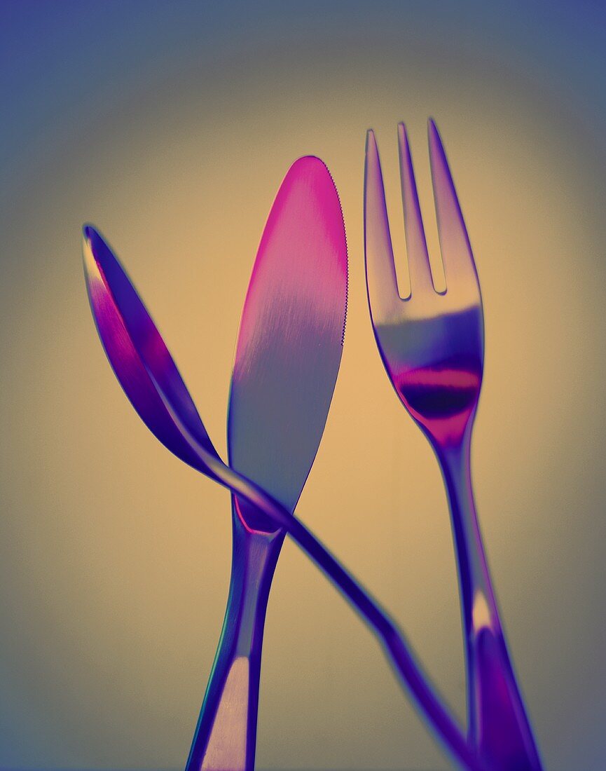 Gabel, Messer und Löffel in rosa-blauem Licht