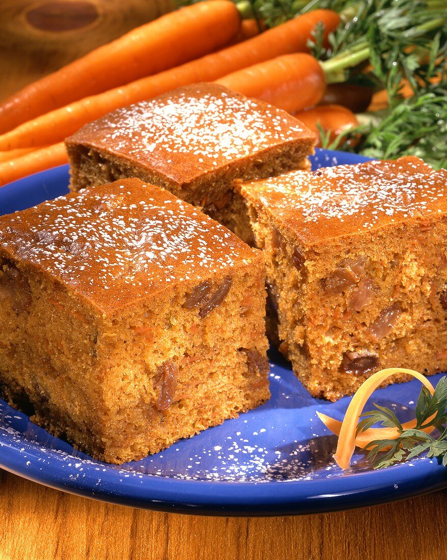 Carrot cake with icing sugar on blue plate