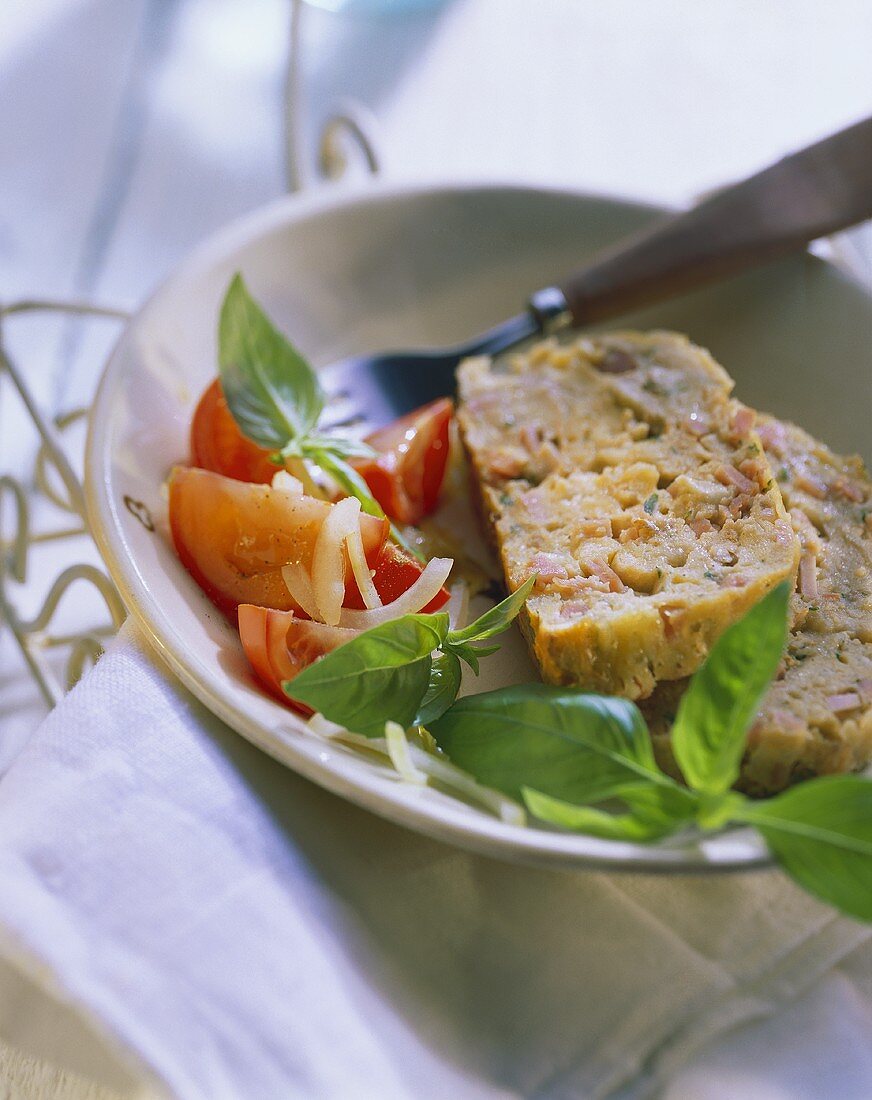 Cheese & ham terrine with tomatoes and basil on plate