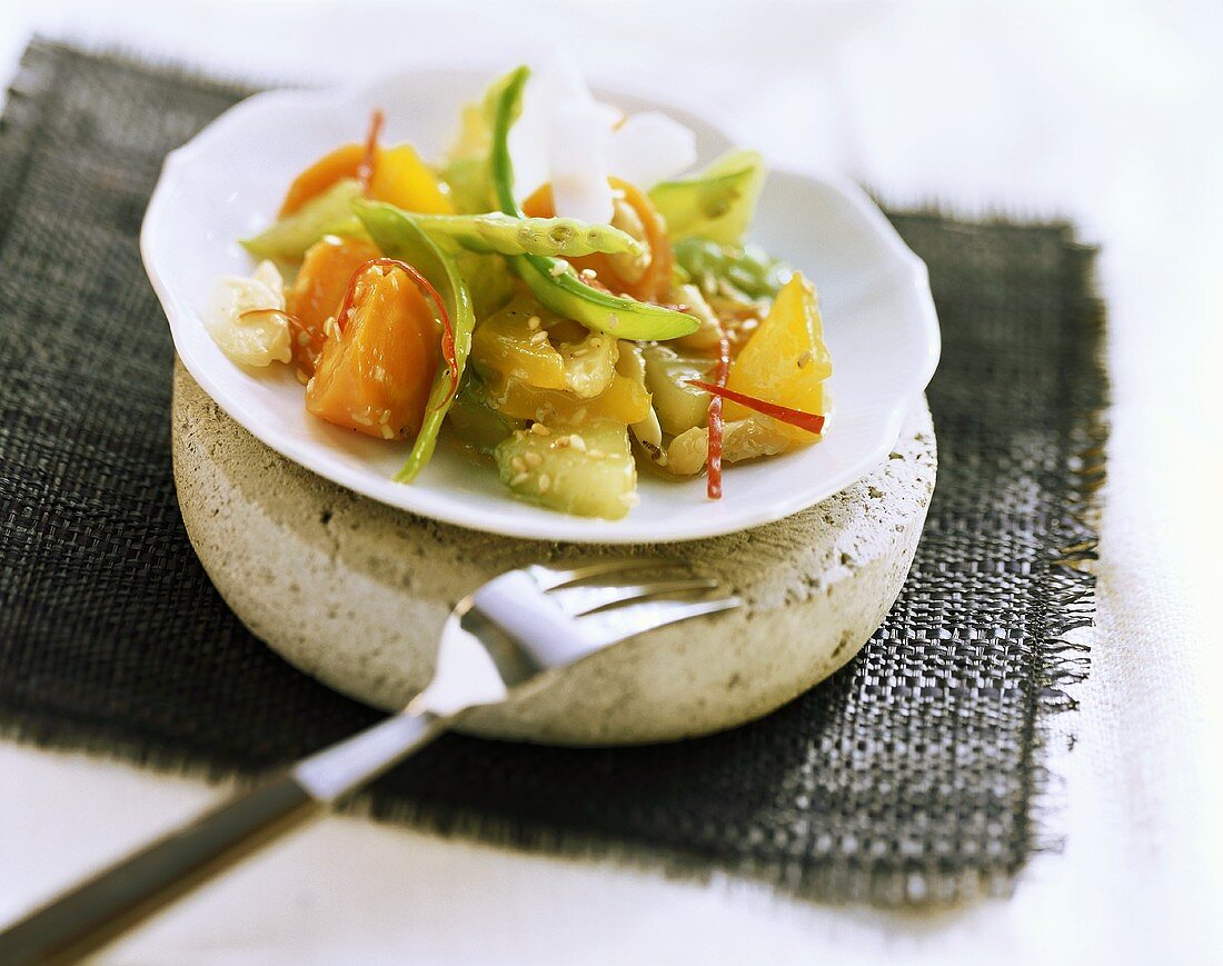 Gemüsecurry mit Sesam und Kokos auf Teller, daneben Gabel