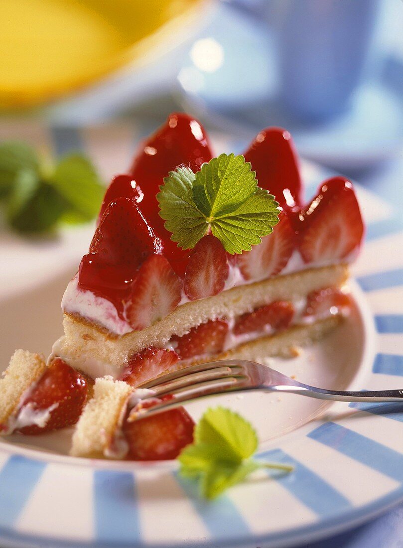 Ein Stück Erdbeer-Quark-Torte, angeschnitten mit Gabel