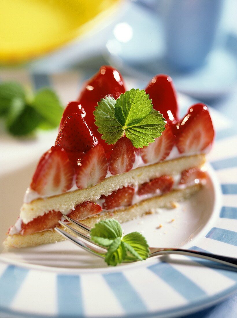 Ein ganzes Stück Erdbeer-Quark-Torte auf Teller mit Gabel