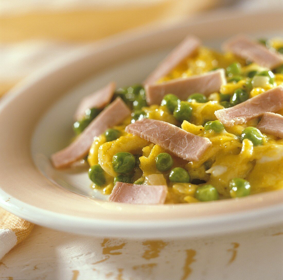 Scrambled egg with peas and ham on plate