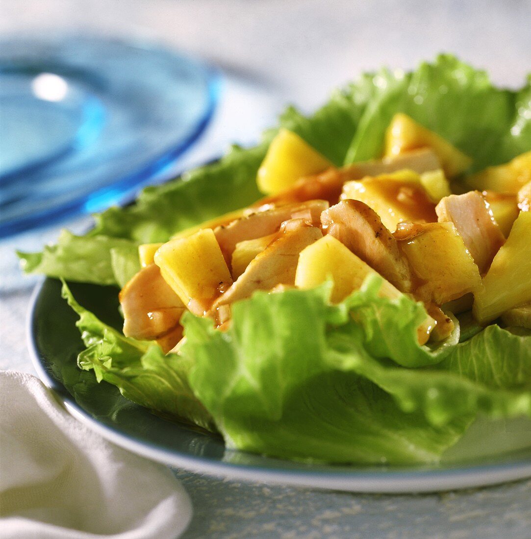 Geflügel-Ananas-Salat auf Eisbergsalatblättern; blauer Teller