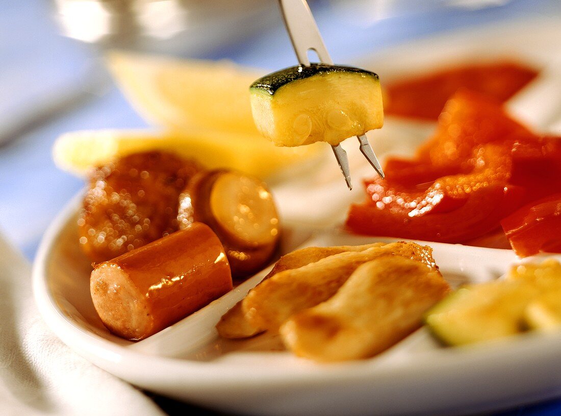 Colourful family fondue with sausages, vegetables etc