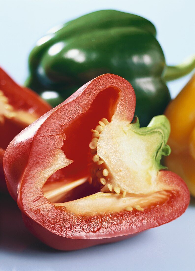 Half a red pepper in front of a green pepper