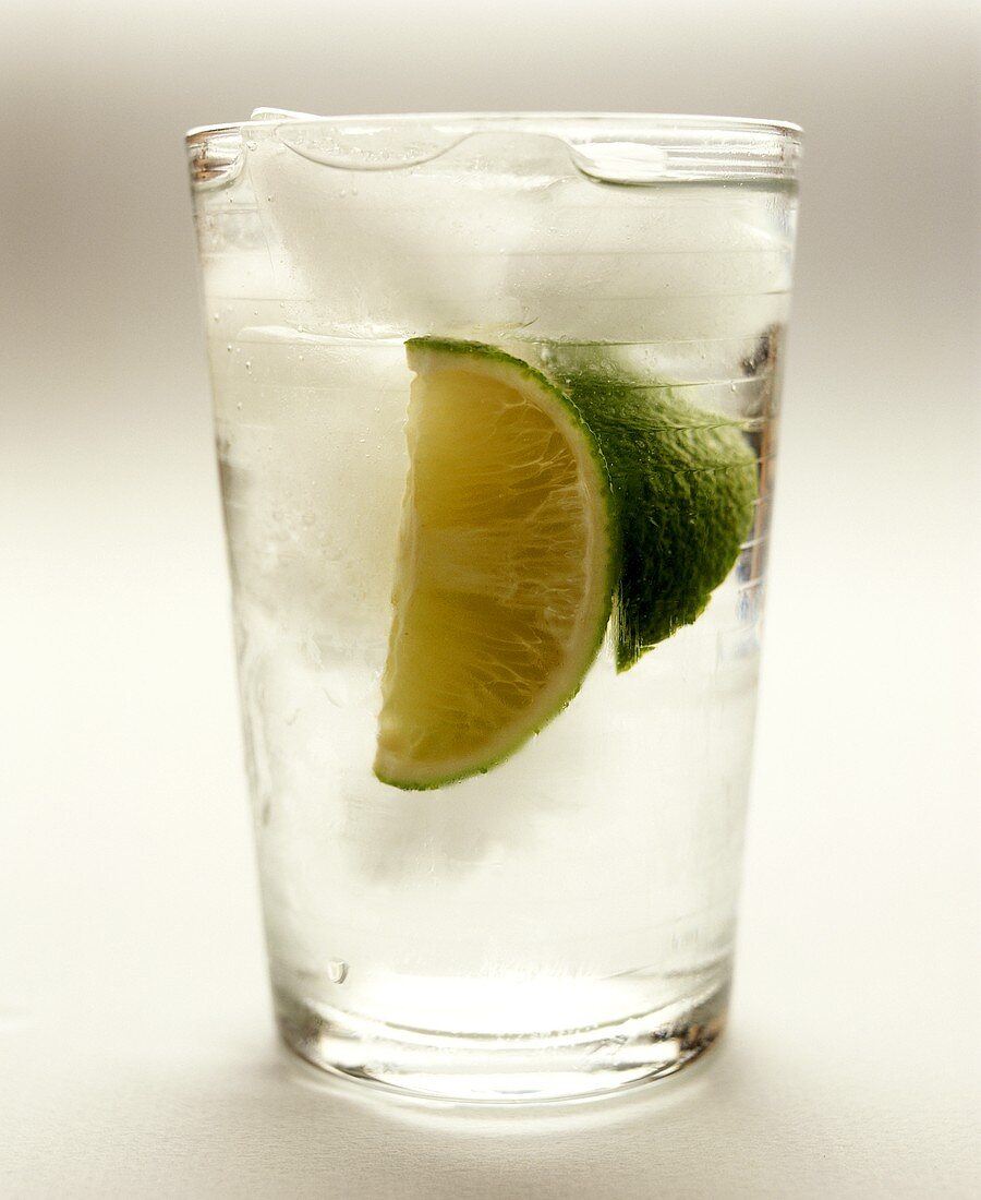 Gin and tonic with lime wedges and ice cubes in glass