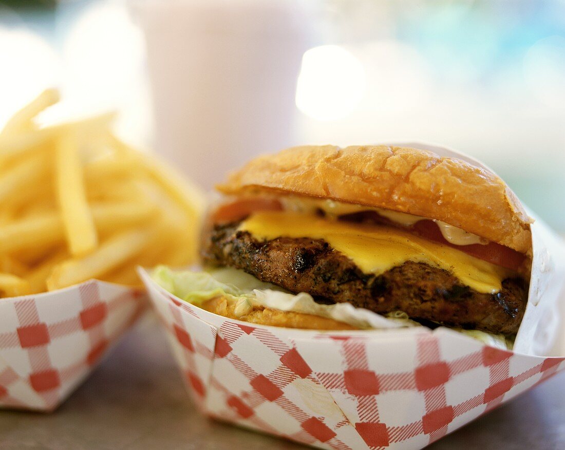 Cheeseburger und Pommes frites in Pappschälchen