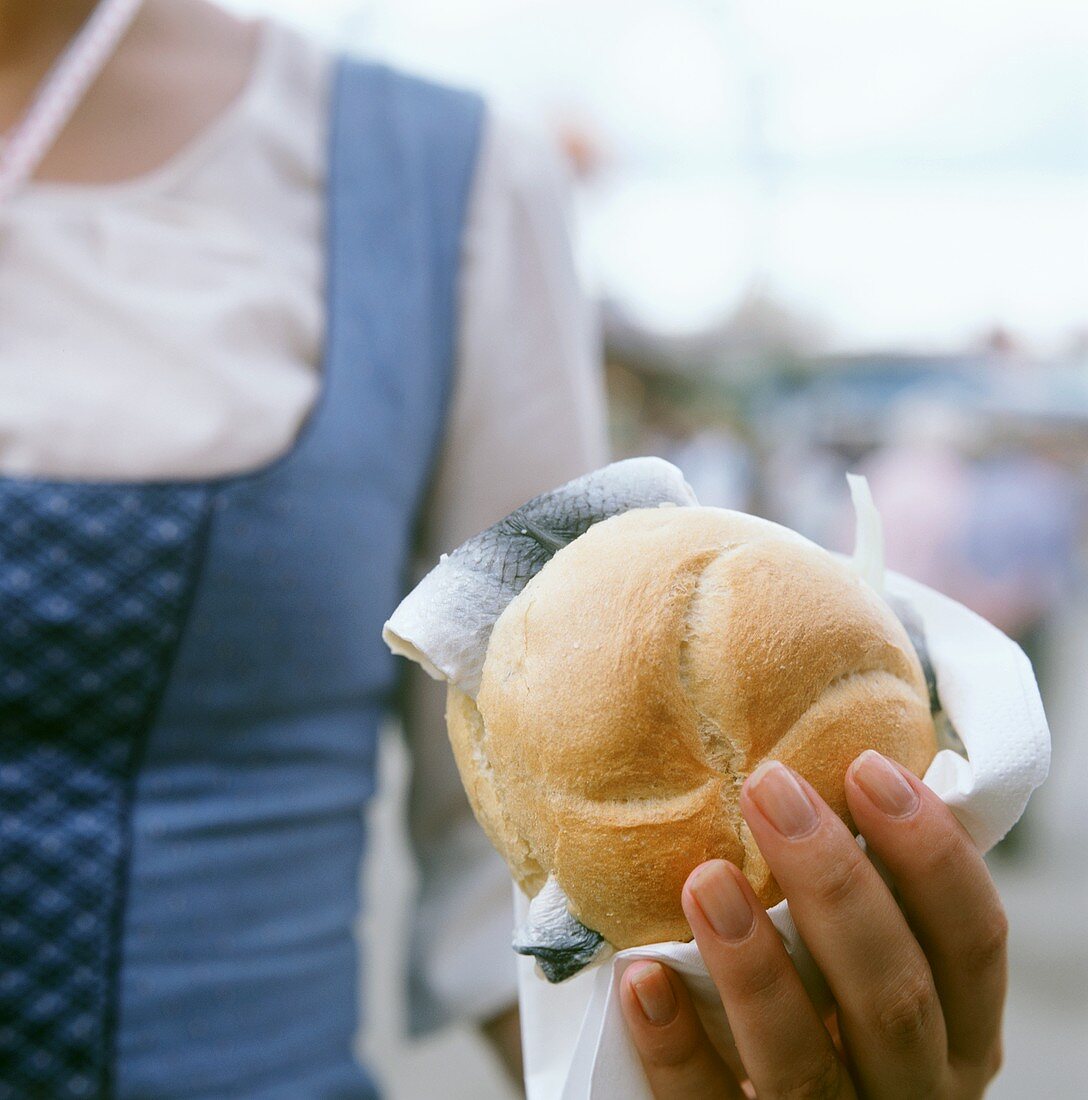 Hand hält Fischsemmel am Oktoberfest