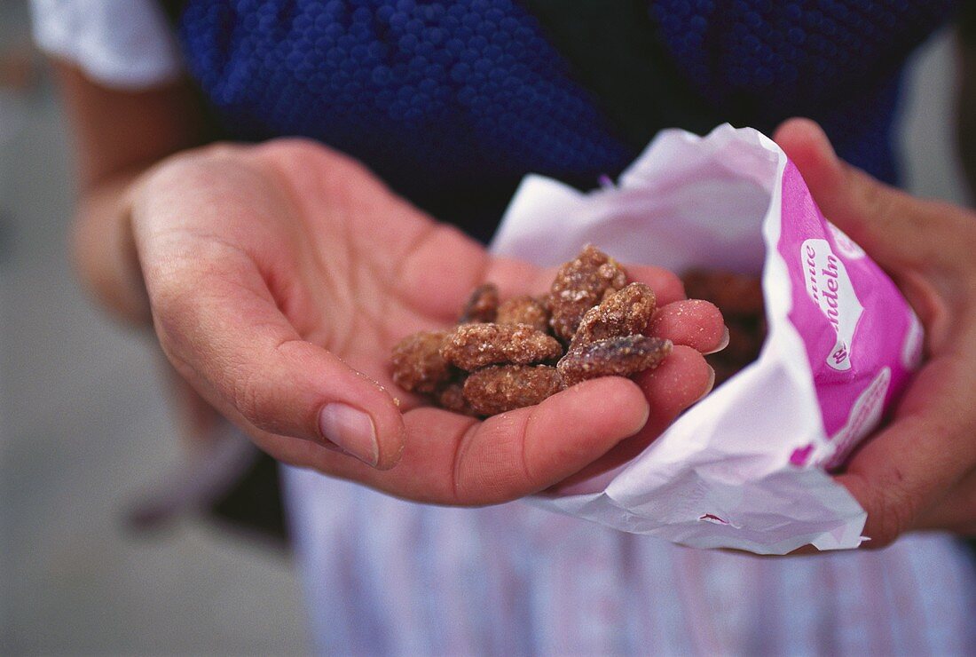 Hand holding roasted almonds