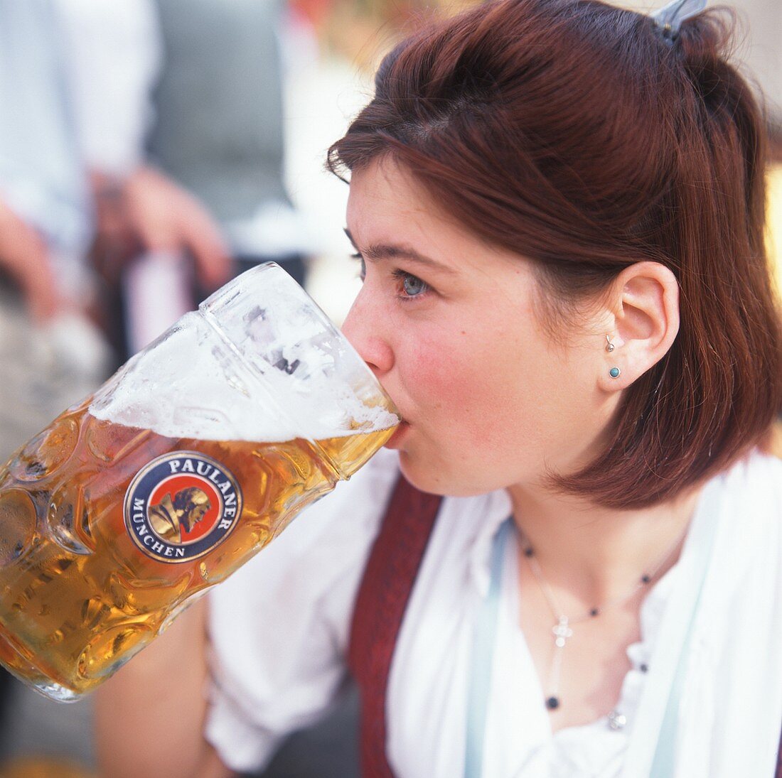 Junge Frau trinkt eine Mass Bier am Oktoberfest